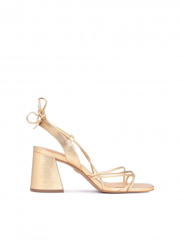 Golden sandals on a block heel laced around the calf