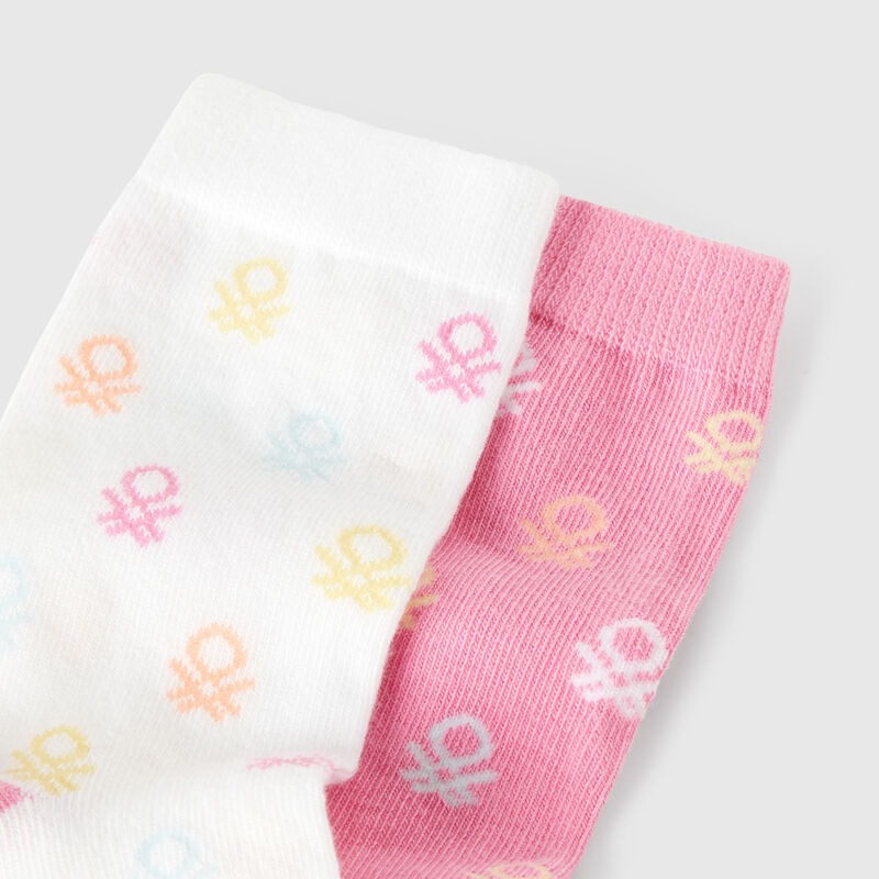 Two pairs of socks with pink and white logos