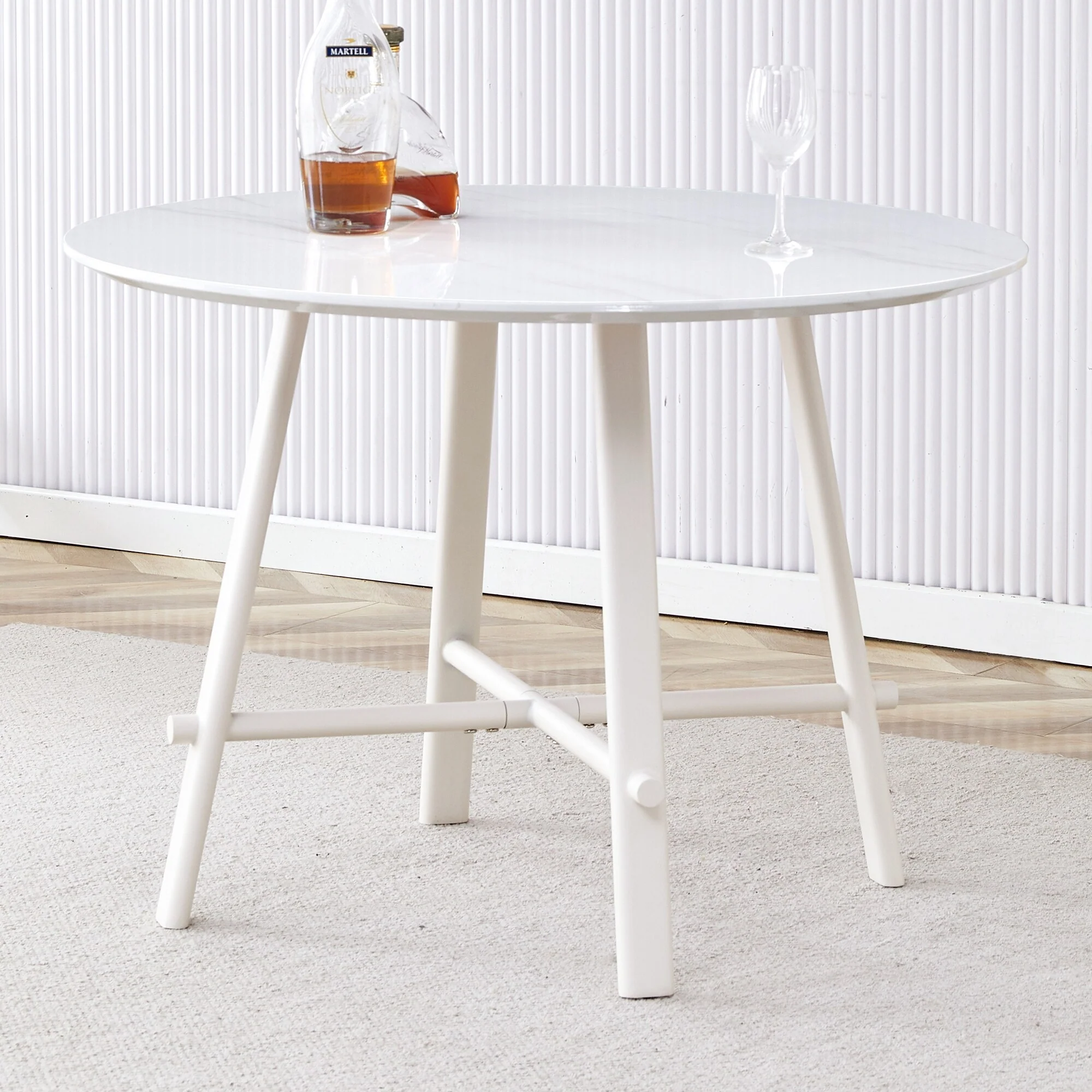 A modern minimalist circular dining table with a 42 inch diameter white patterned tabletop and white metal legs
