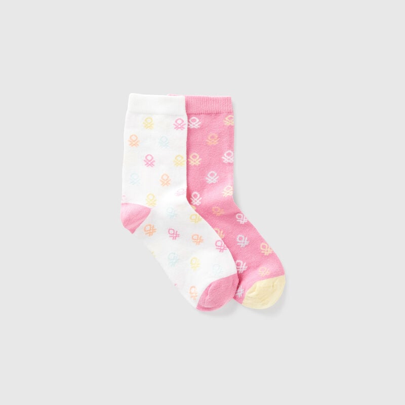 Two pairs of socks with pink and white logos