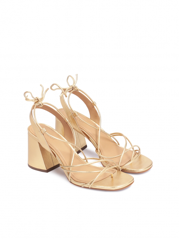 Golden sandals on a block heel laced around the calf