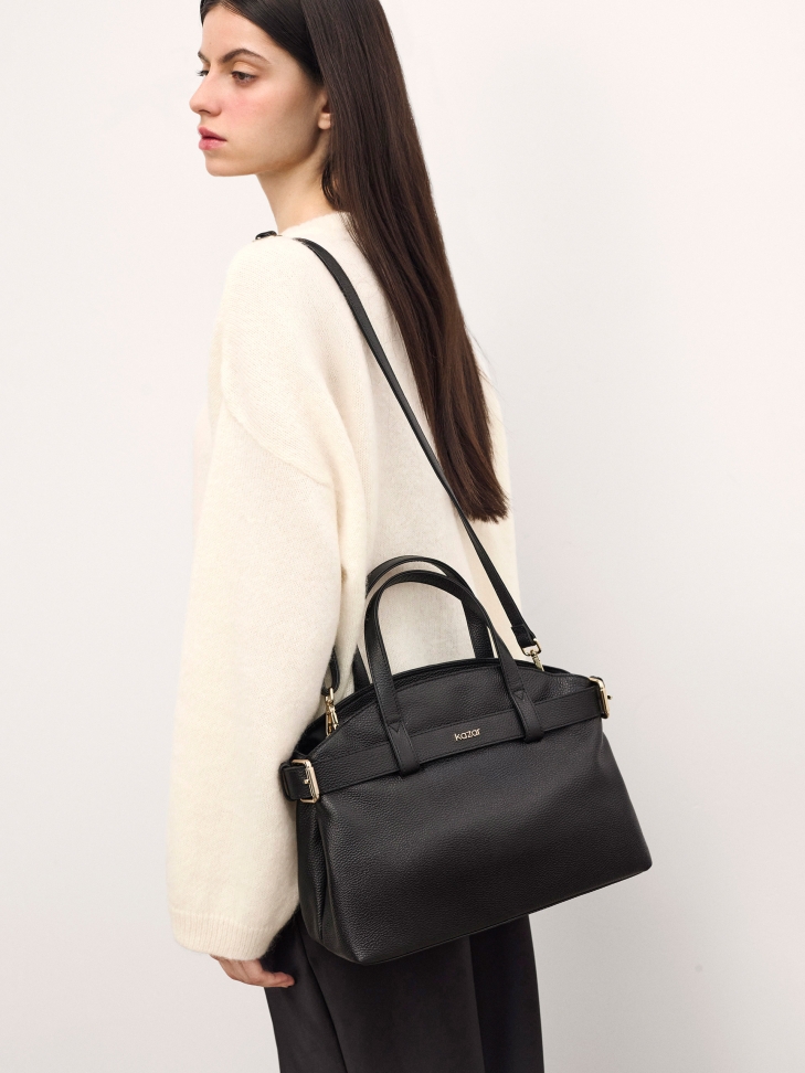 Black leather handbag with decorative strap and functional interior