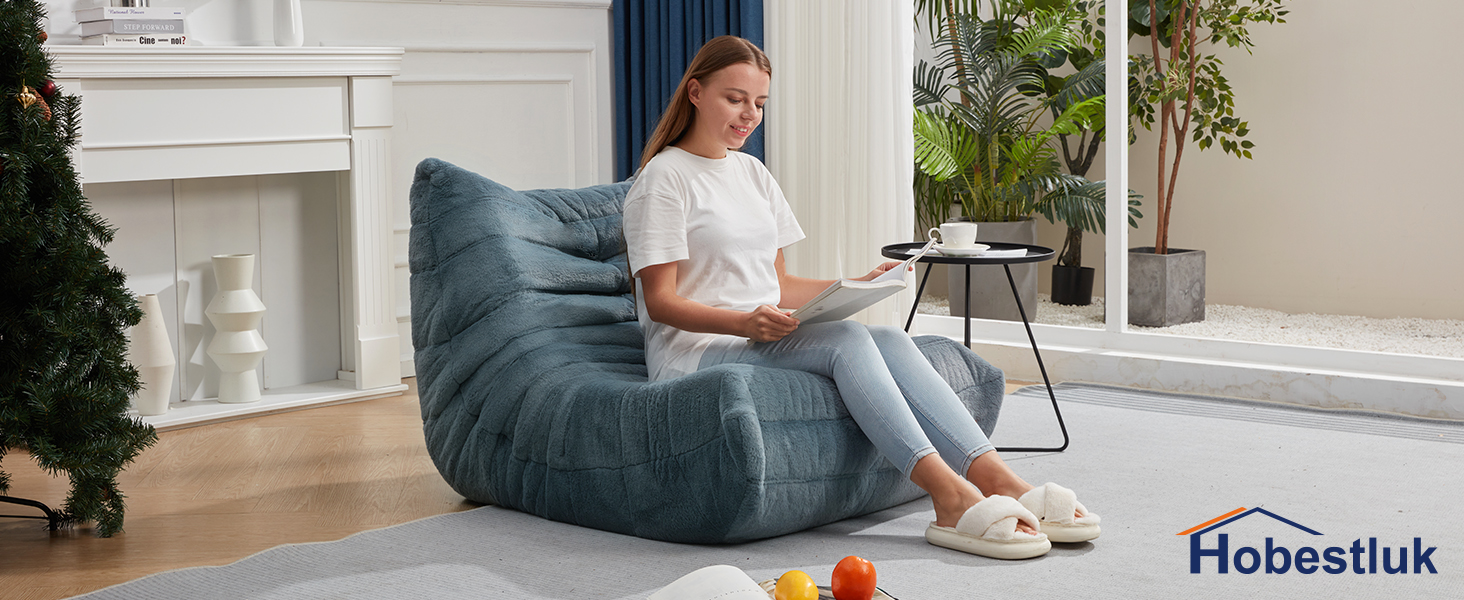 a girl is sitting one the huge bean bag to read a book
