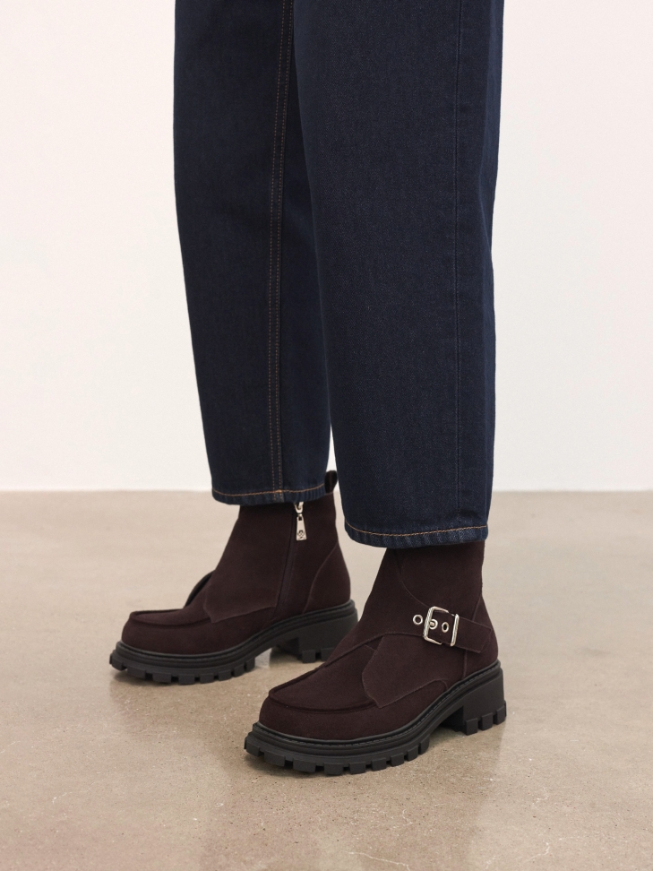 Brown suede boots on a solid sole with a decorative buckle
