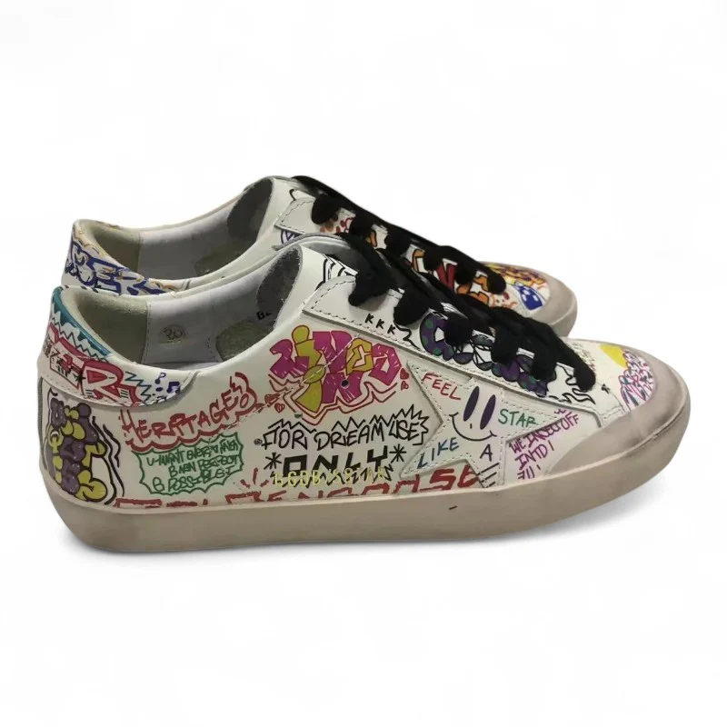 The Super-Star sneakers feature a white leather upper adorned with a vibrant multicolored graffiti print