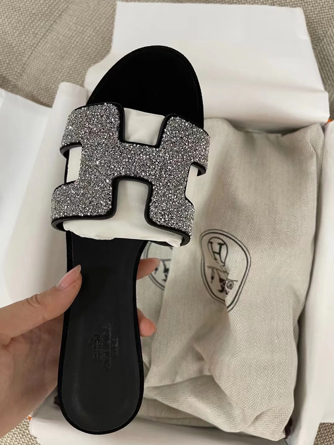Тапочки Hermes с буквой H — черные с серебряными стразами.