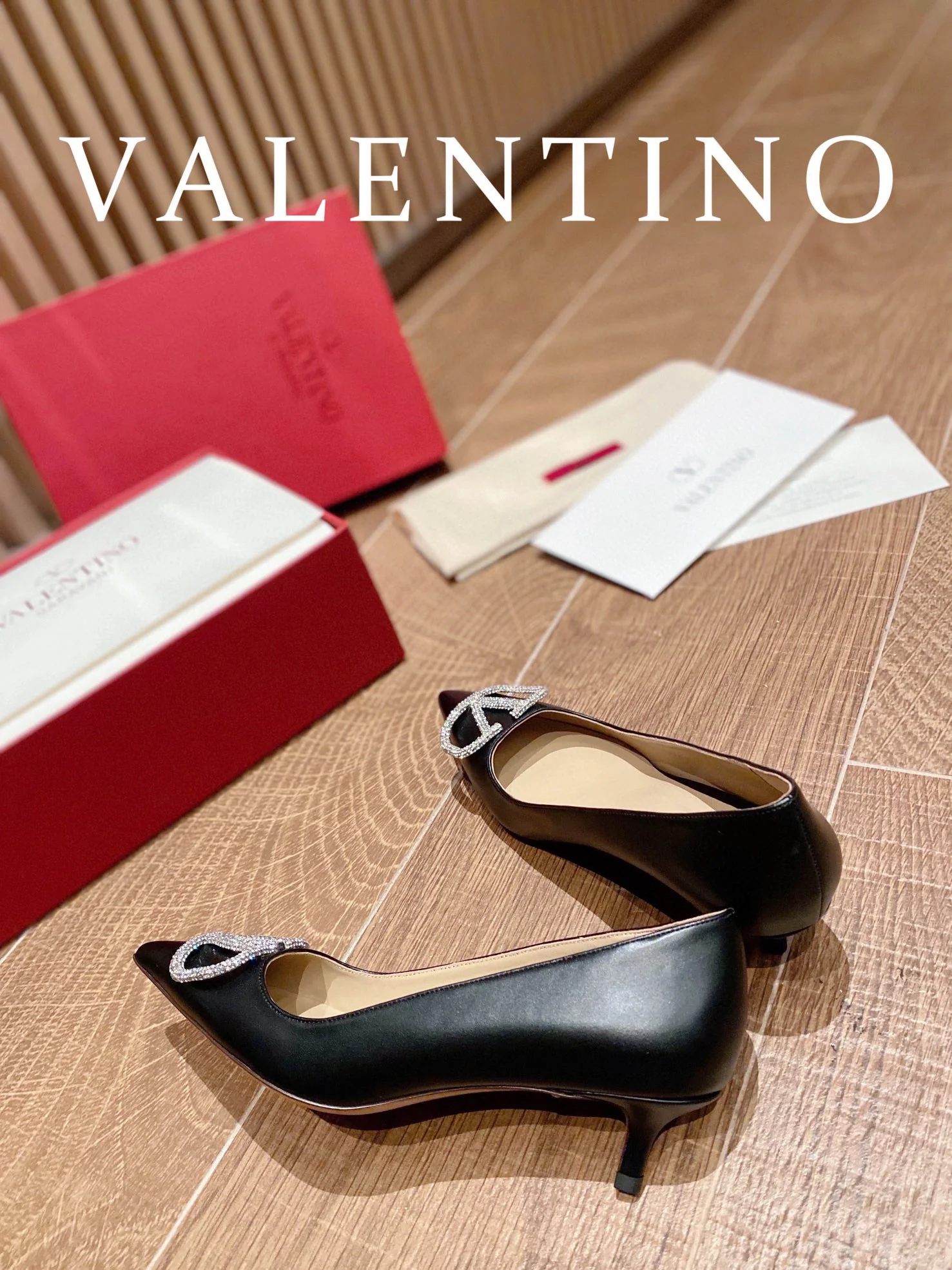 Туфли Valentino на каблуке с V-образным вырезом и бриллиантовой пряжкой — черные.