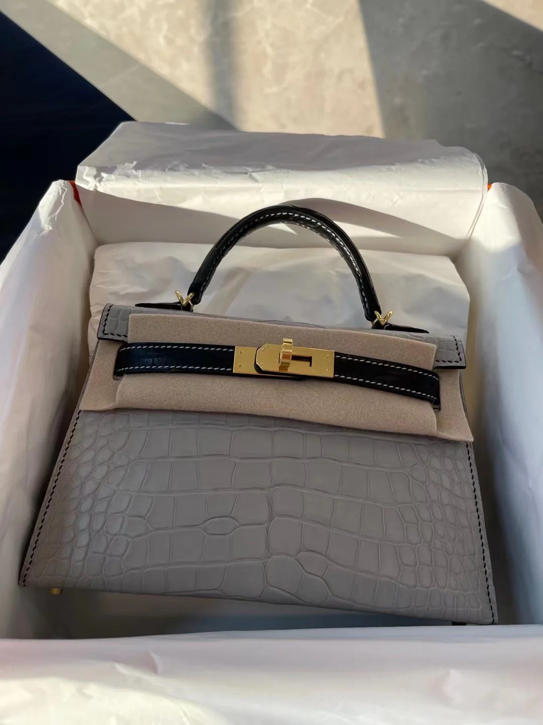 Миниатюрная сумка Hermes Kelly Mini 2-го поколения из матовой кожи аллигатора — жемчужно-серая и черная с золотой фурнитурой.