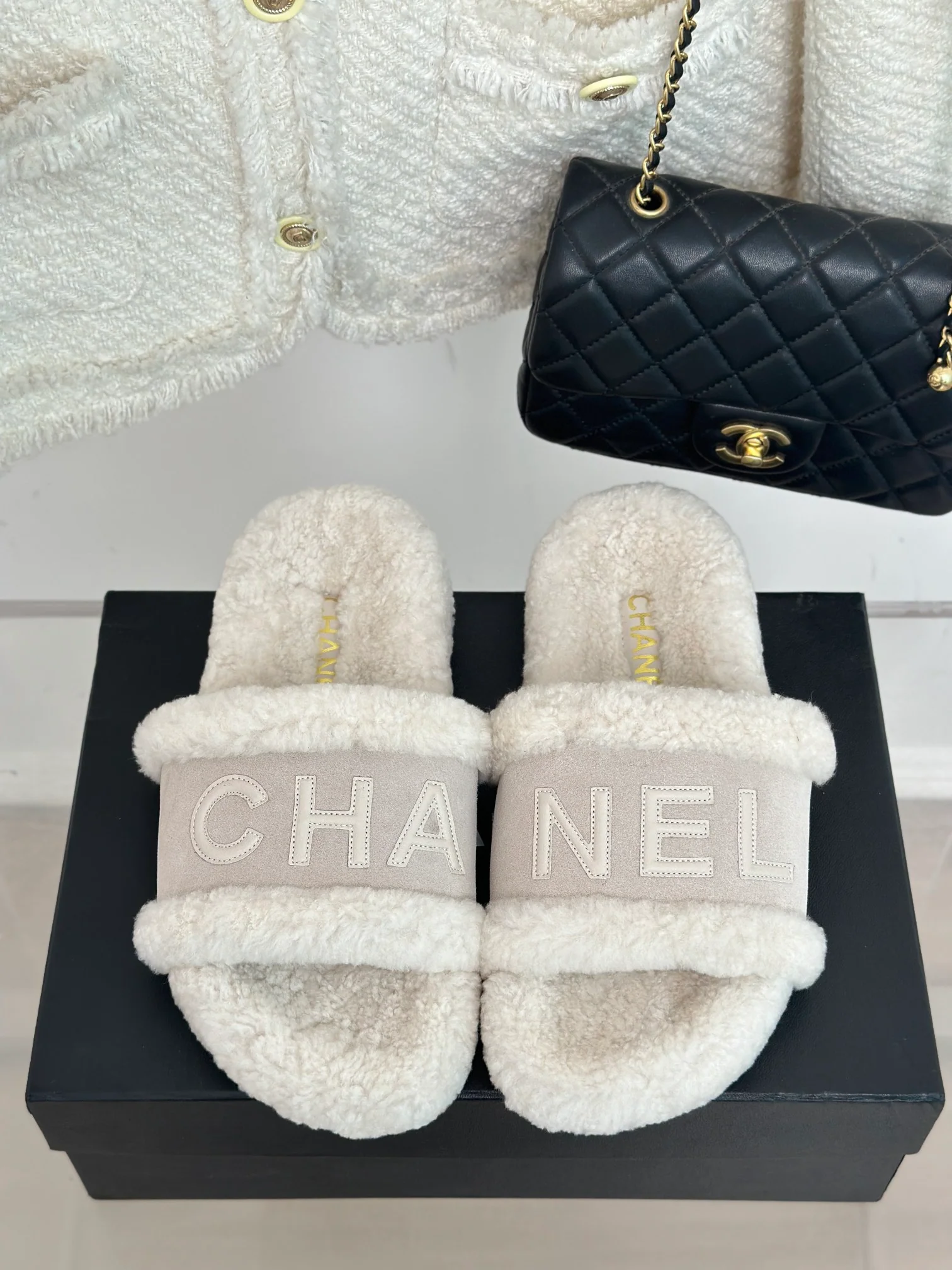 Новинка сезона осень/зима 2023 от Chanel — Меховые тапочки с буквенным принтом, кремовый цвет.