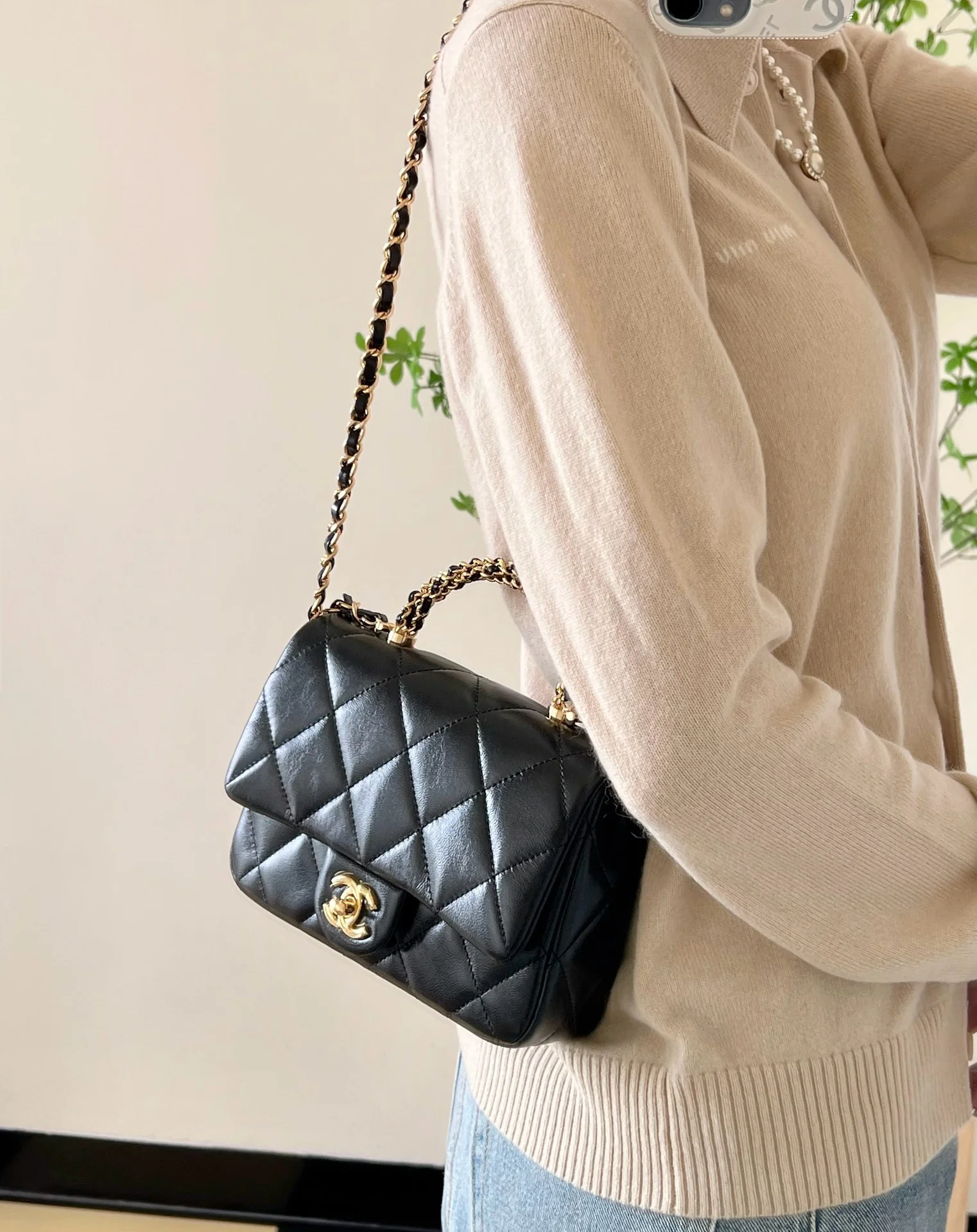 Маленькая черная сумка Chanel с клапаном и поворотной ручкой.