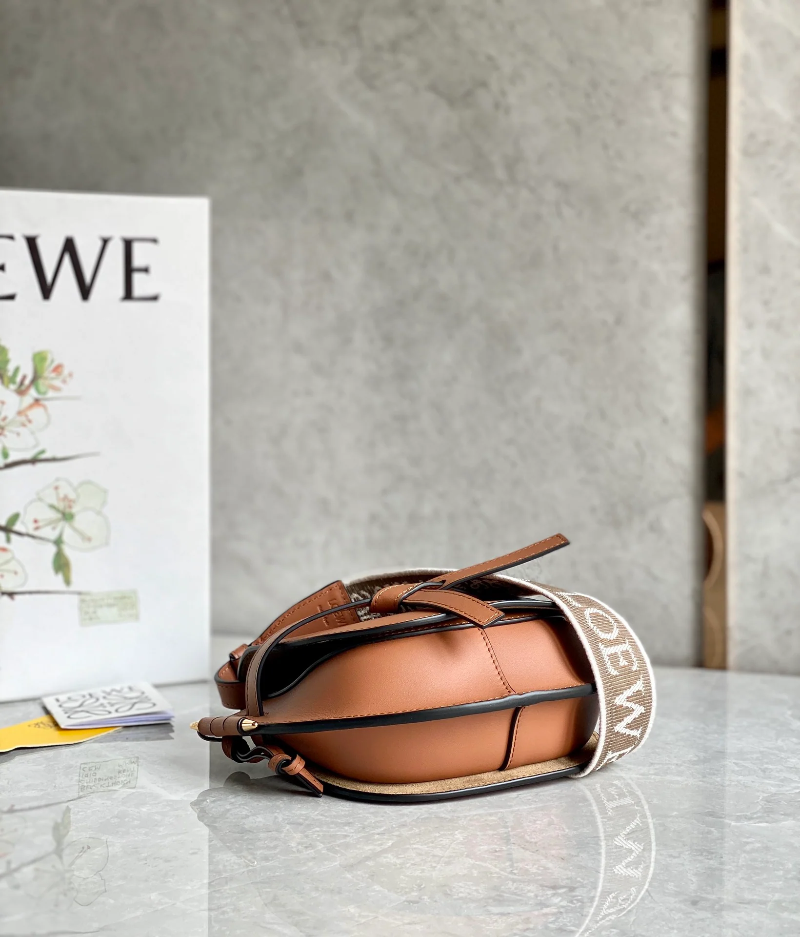Сумка Loewe Gate Mini 21x12x5x9x5 см с широким плечевым ремнем и надписью.
