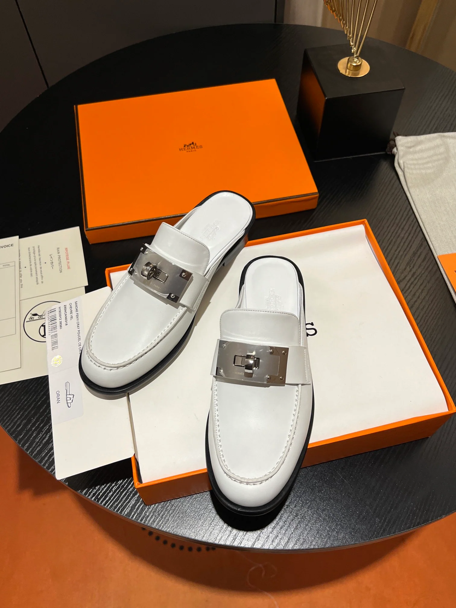 Мюли Hermes 2024 с металлической пряжкой в ??виде буквы H — белые.
