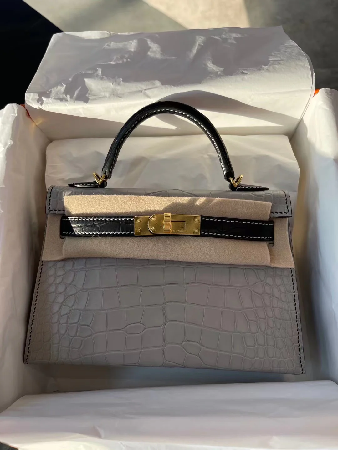 Миниатюрная сумка Hermes Kelly Mini 2-го поколения из матовой кожи аллигатора — жемчужно-серая и черная с золотой фурнитурой.