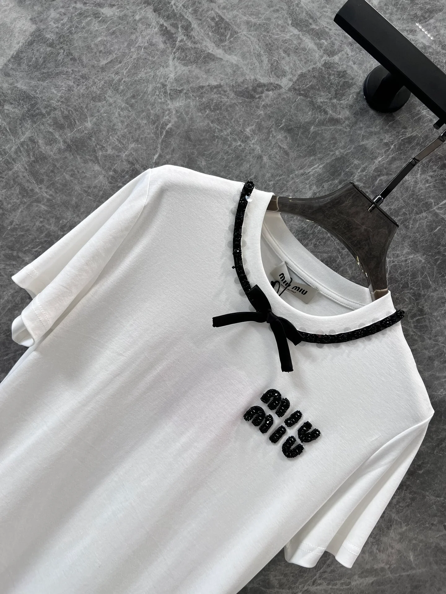 Miu Miu-2404-24 Новая модель для ранней весны: галстук ручной работы с бисером и бантом в виде буквы, футболка с коротким рукавом и круглым вырезом.