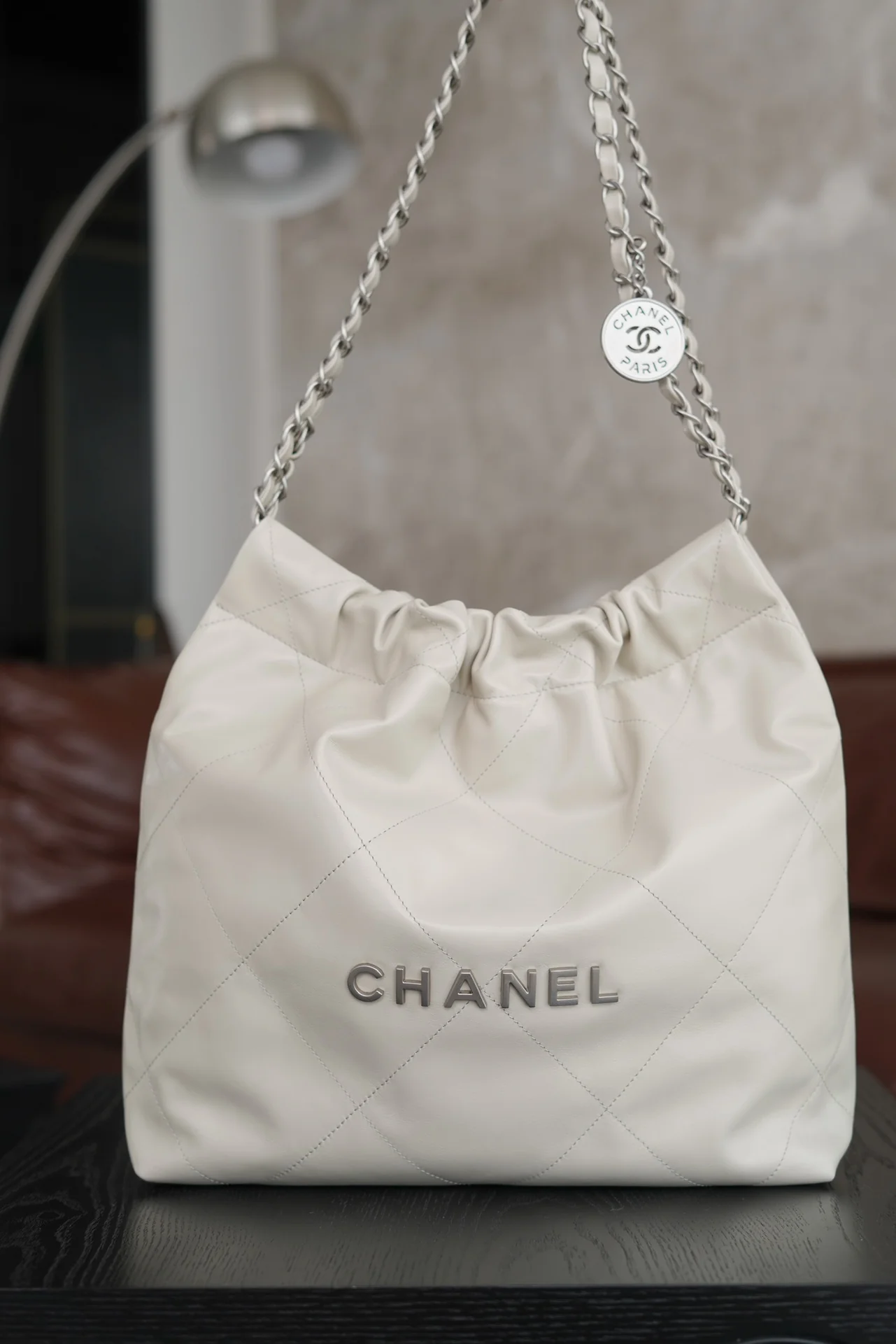 Маленькая белая сумочка Chanel с серебряной пряжкой на задней части.