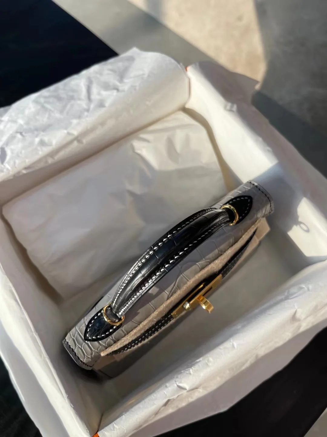 Миниатюрная сумка Hermes Kelly Mini 2-го поколения из матовой кожи аллигатора — жемчужно-серая и черная с золотой фурнитурой.