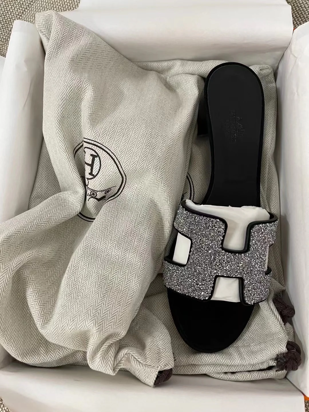 Тапочки Hermes с буквой H — черные с серебряными стразами.