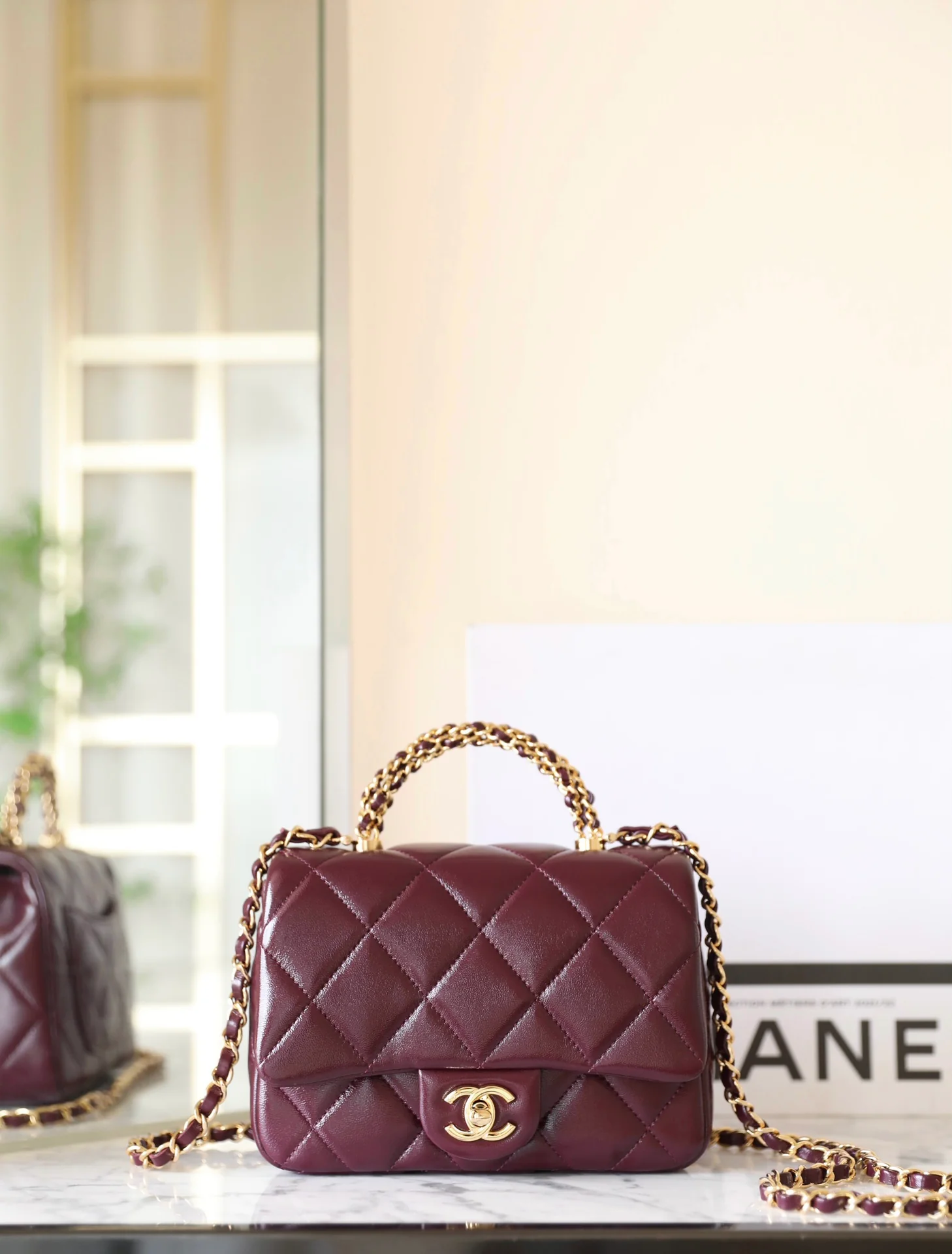 Маленькая бордовая сумочка Chanel с клапаном и привинчивающейся ручкой.