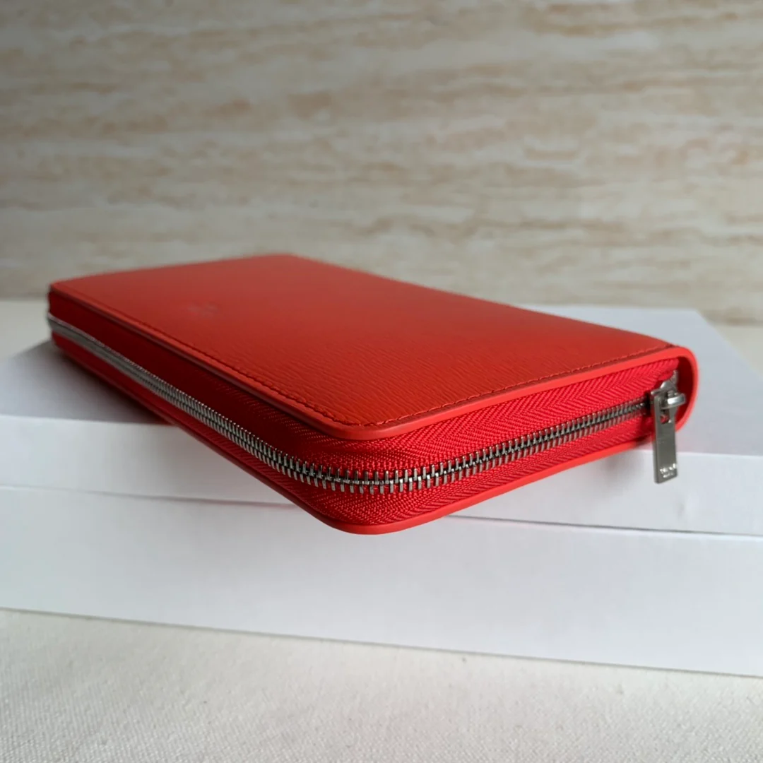 Кошелек Celine с длинной молнией — оранжево-красный узор в виде ряби на воде.