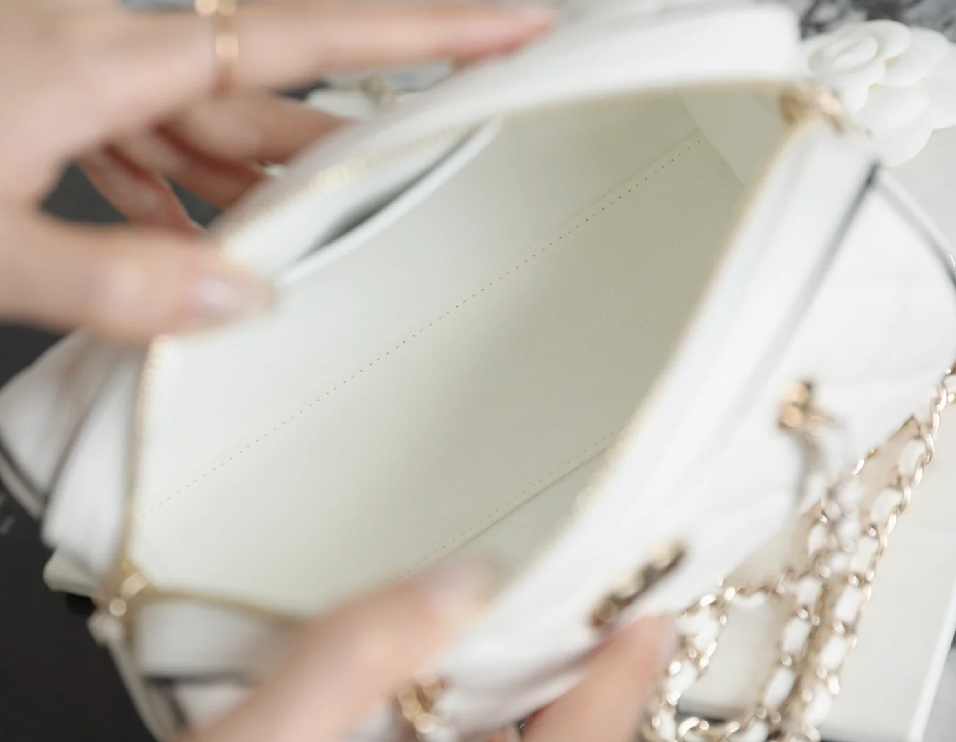 Мини-сумка-котелок Chanel 25p из овечьей кожи, белая с черной отделкой и светло-золотистой пряжкой.