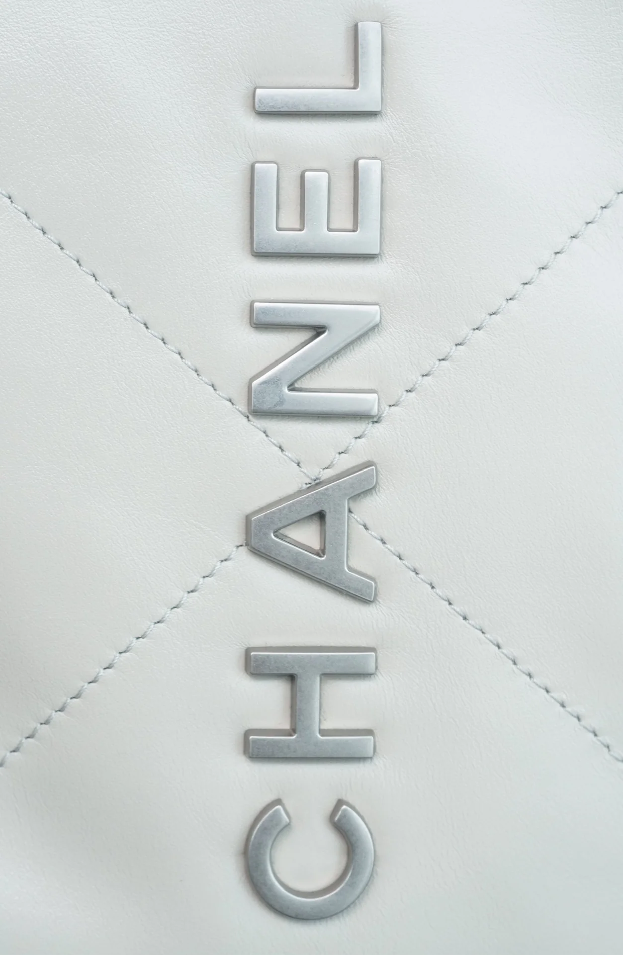 Маленькая белая сумочка Chanel с серебряной пряжкой на задней части.