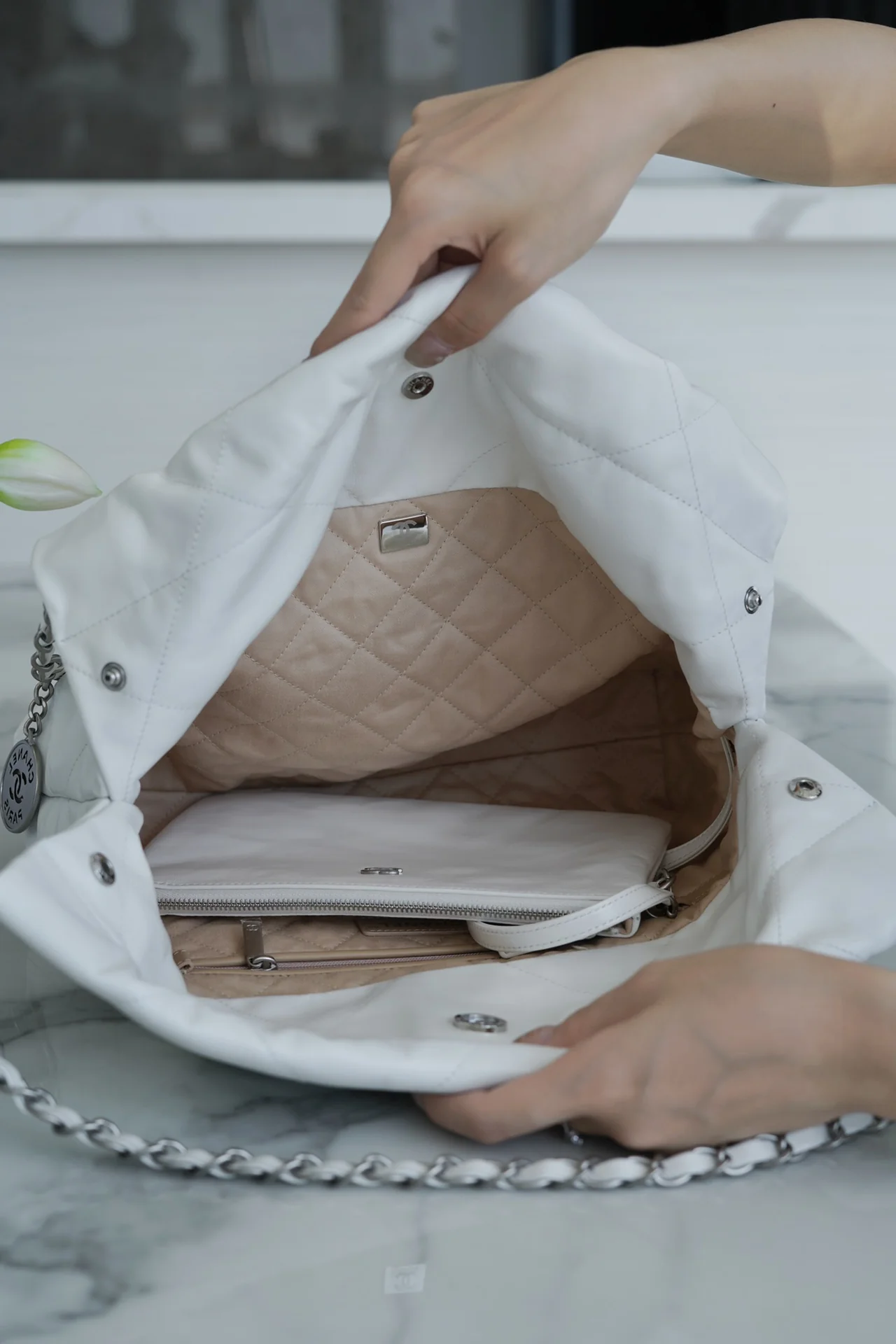 Сумочка Chanel No. 22 — маленькая, белая, серебристая.