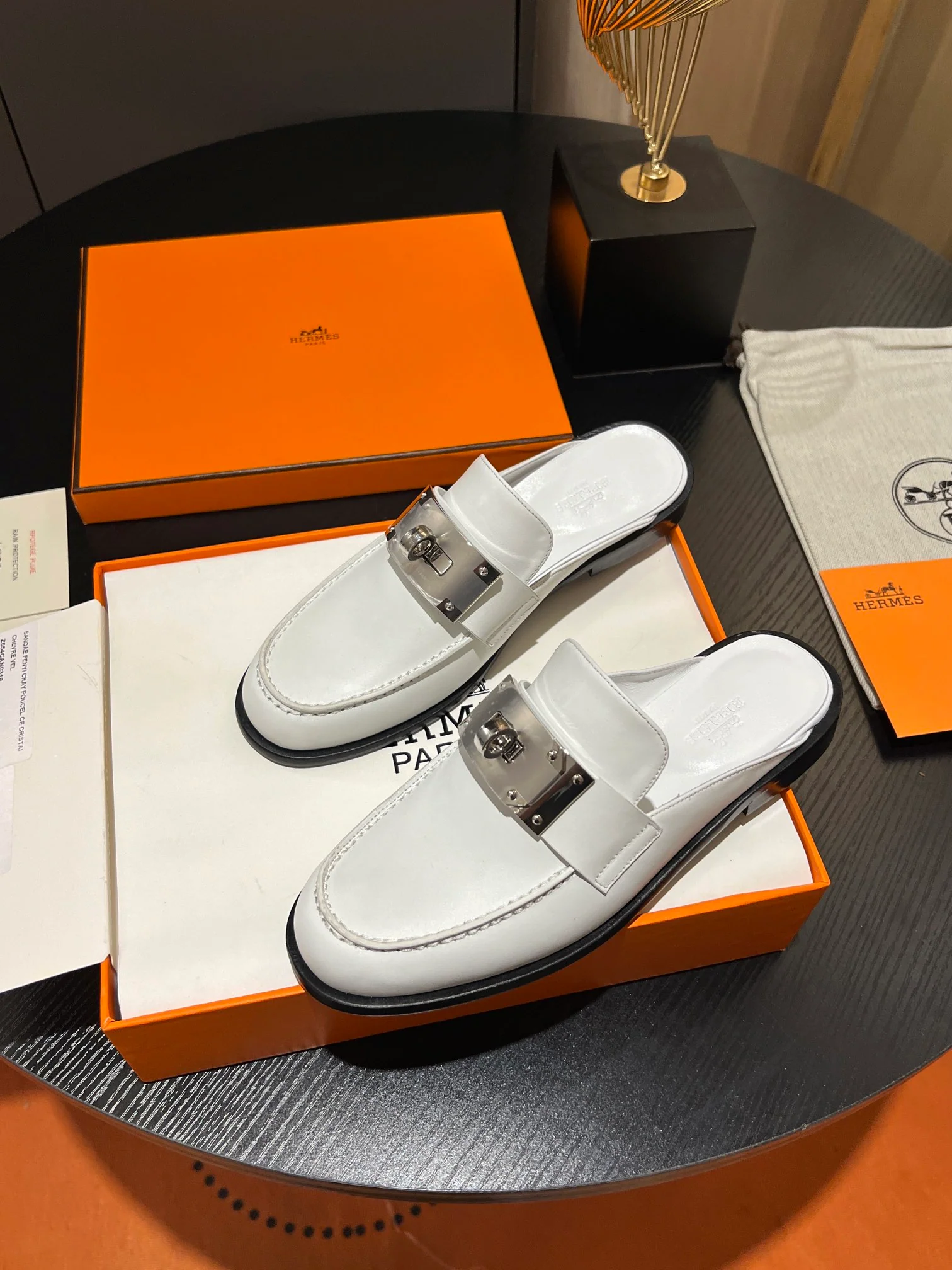 Мюли Hermes 2024 с металлической пряжкой в ??виде буквы H — белые.