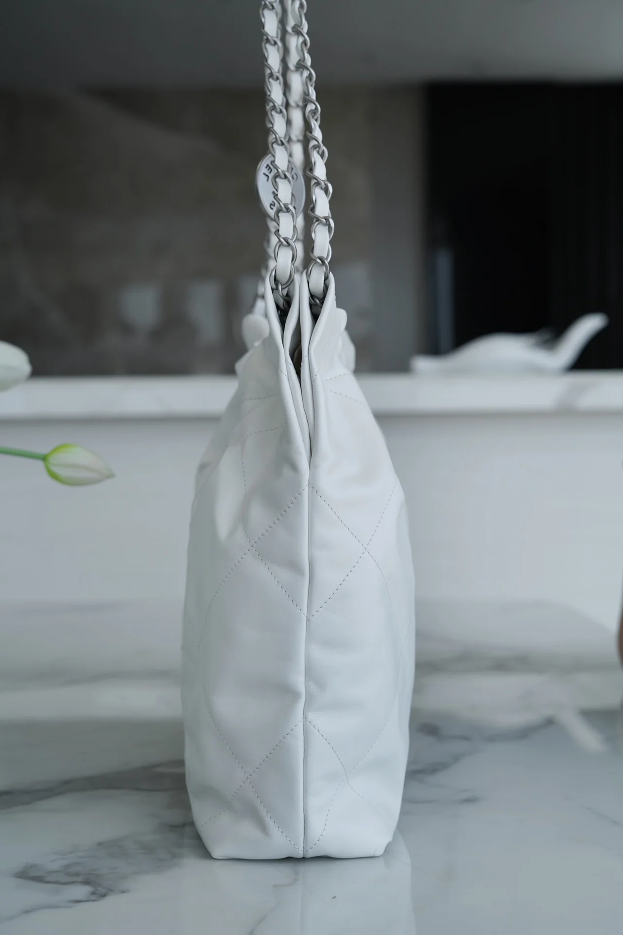 Сумочка Chanel No. 22 — маленькая, белая, серебристая.