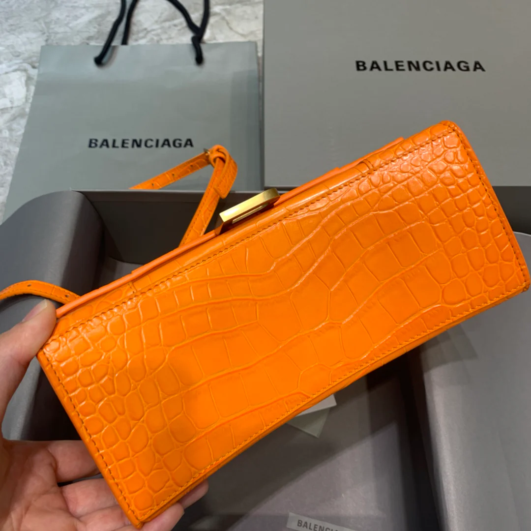 Сумка Balenciaga Hourglass — оранжевая с тиснением под крокодиловую кожу и золотой пряжкой.