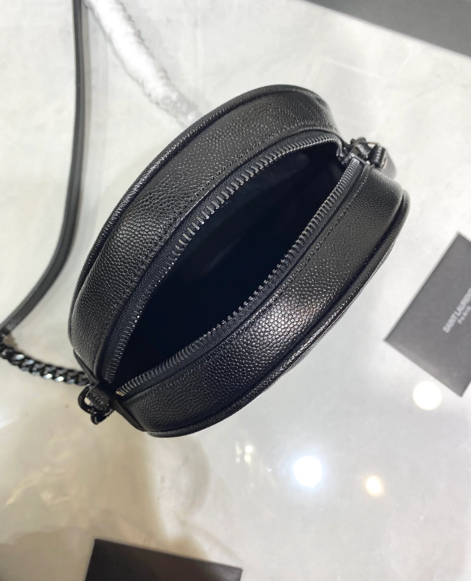 Маленькая круглая сумка YSL Vinyle - черная с черной пряжкой.