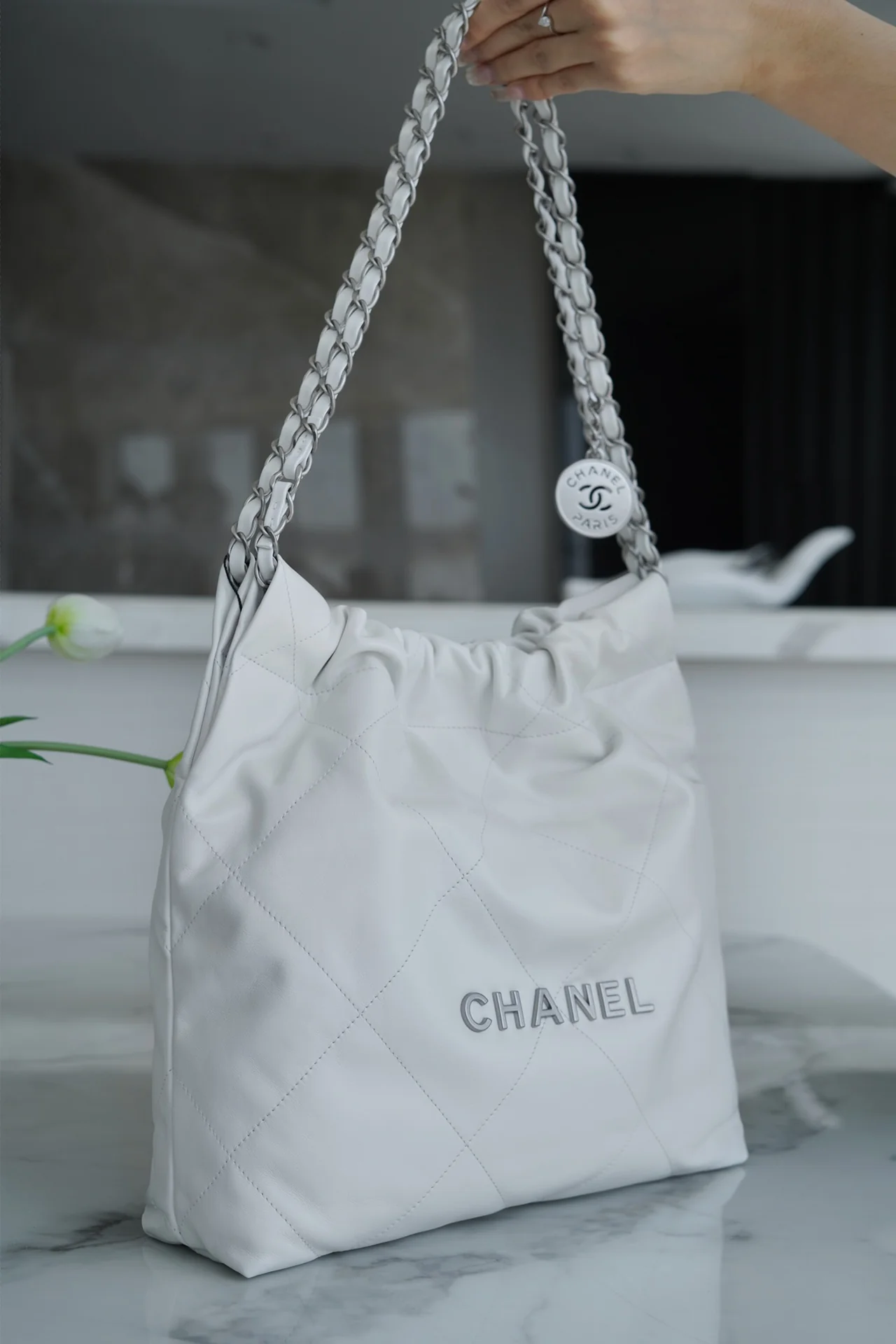 Сумочка Chanel No. 22 — маленькая, белая, серебристая.