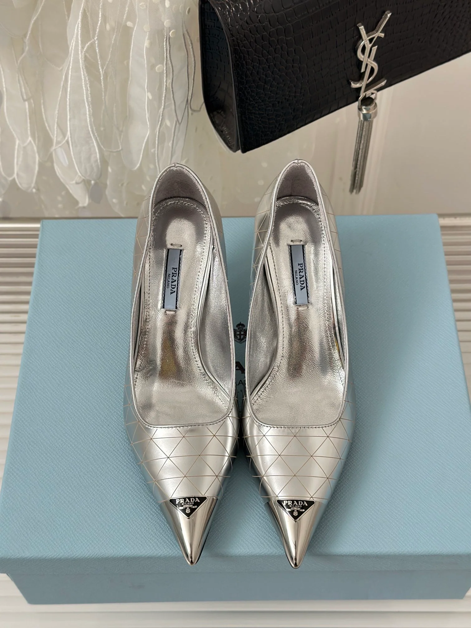 Новинка сезона весна/лето 2023 от Prada - Туфли на высоком каблуке с острым носком и треугольным логотипом - серебристые.