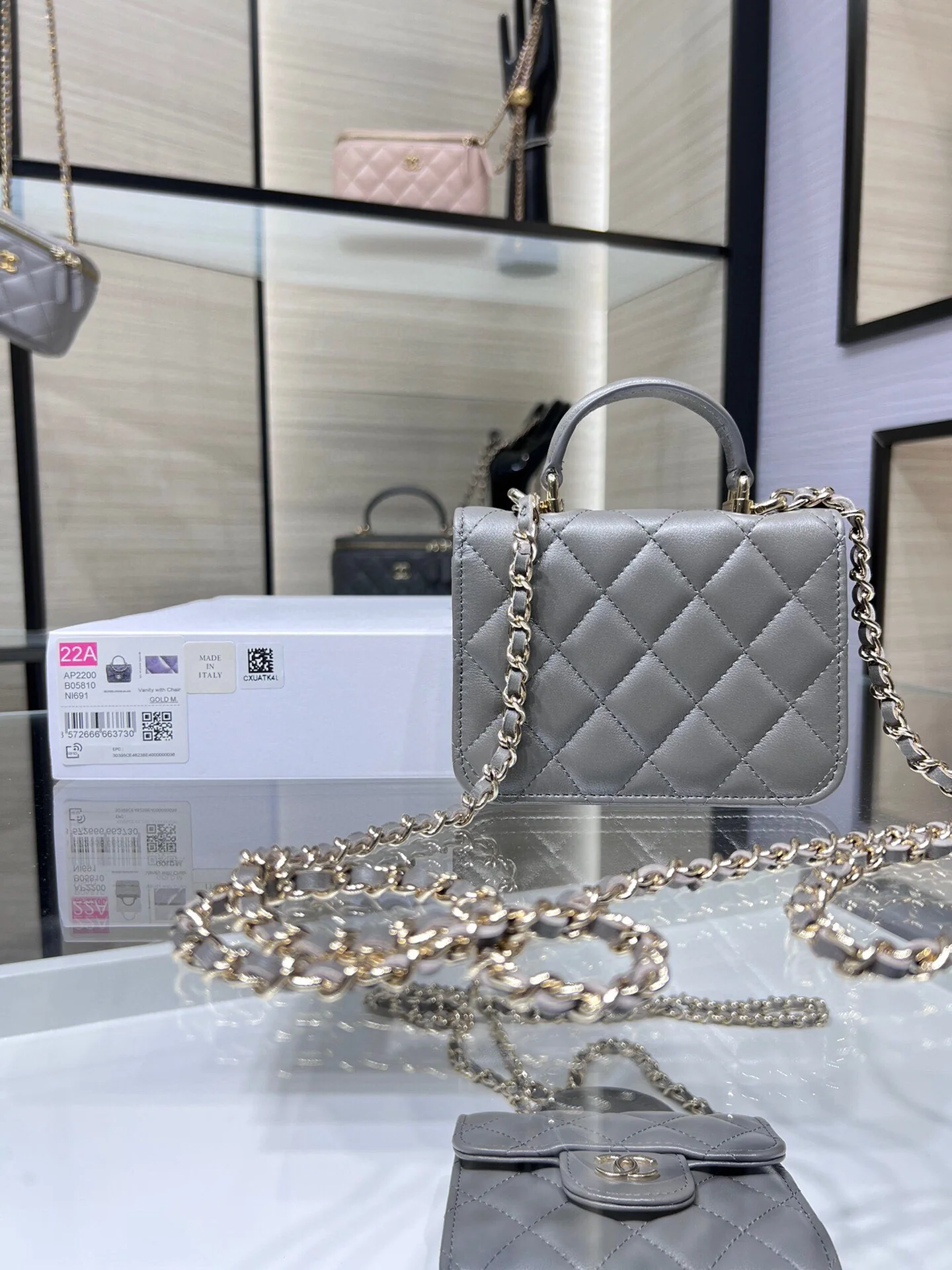 Сумка Chanel из коллекции Métiers d'Art 2022 года — маленькая сумка с цепочкой и ручкой — серая.