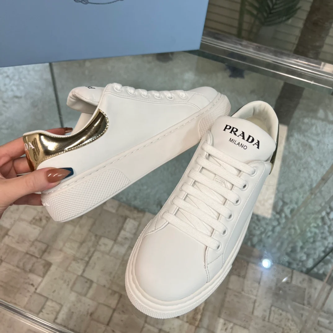 Новинка сезона весна/лето 2023 от Prada - белые кроссовки с цветовыми блоками и золотистой отделкой.