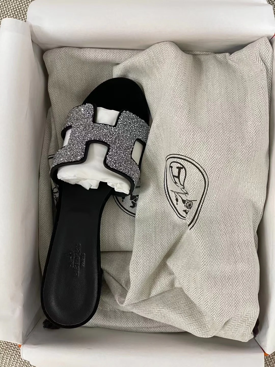 Тапочки Hermes с буквой H — черные с серебряными стразами.