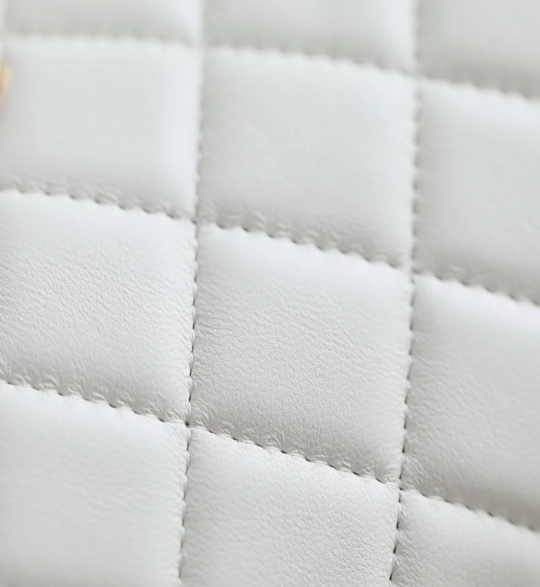 Мини-сумка-котелок Chanel 25p из овечьей кожи, белая с черной отделкой и светло-золотистой пряжкой.