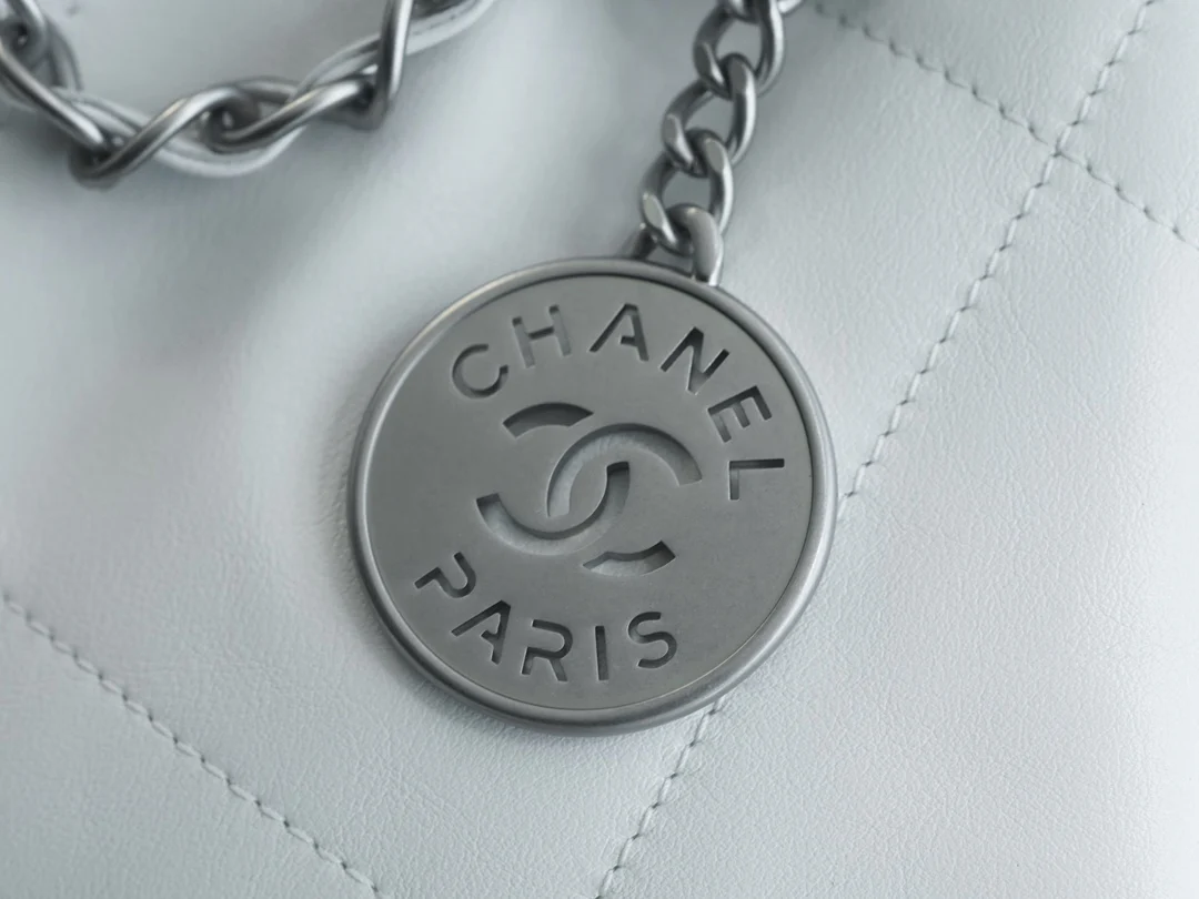 Сумочка Chanel No. 22 — маленькая, белая, серебристая.