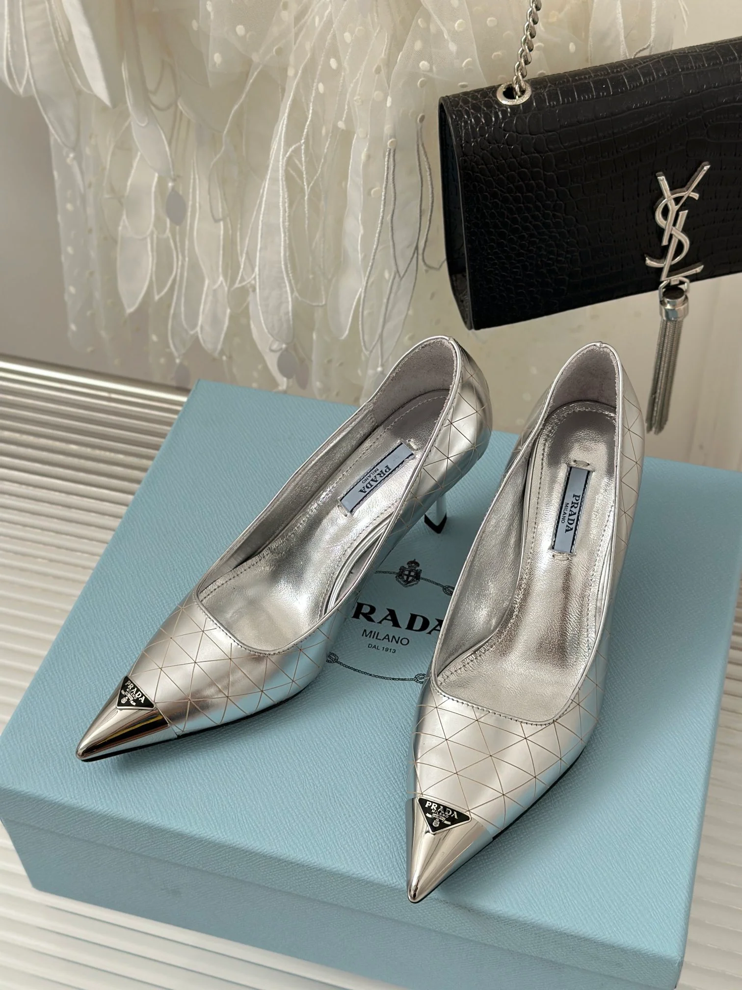 Новинка сезона весна/лето 2023 от Prada - Туфли на высоком каблуке с острым носком и треугольным логотипом - серебристые.