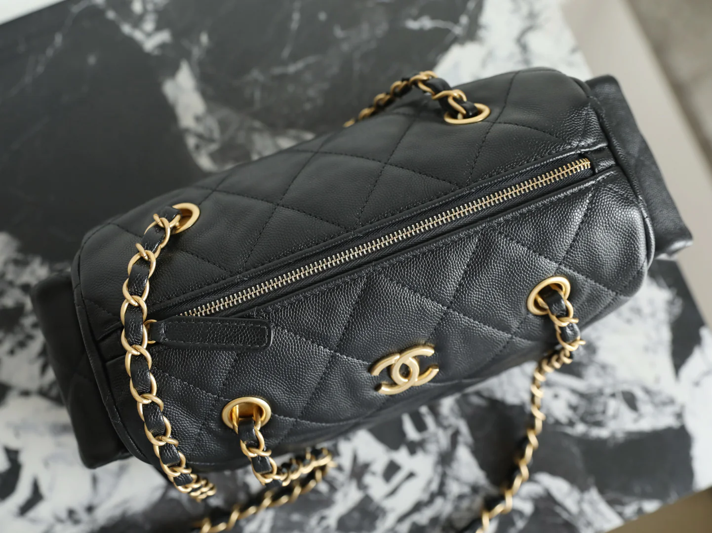 Сумка-боулинг Chanel 25k с двумя карманами — черная кожа с золотой пряжкой и маленьким шариком.