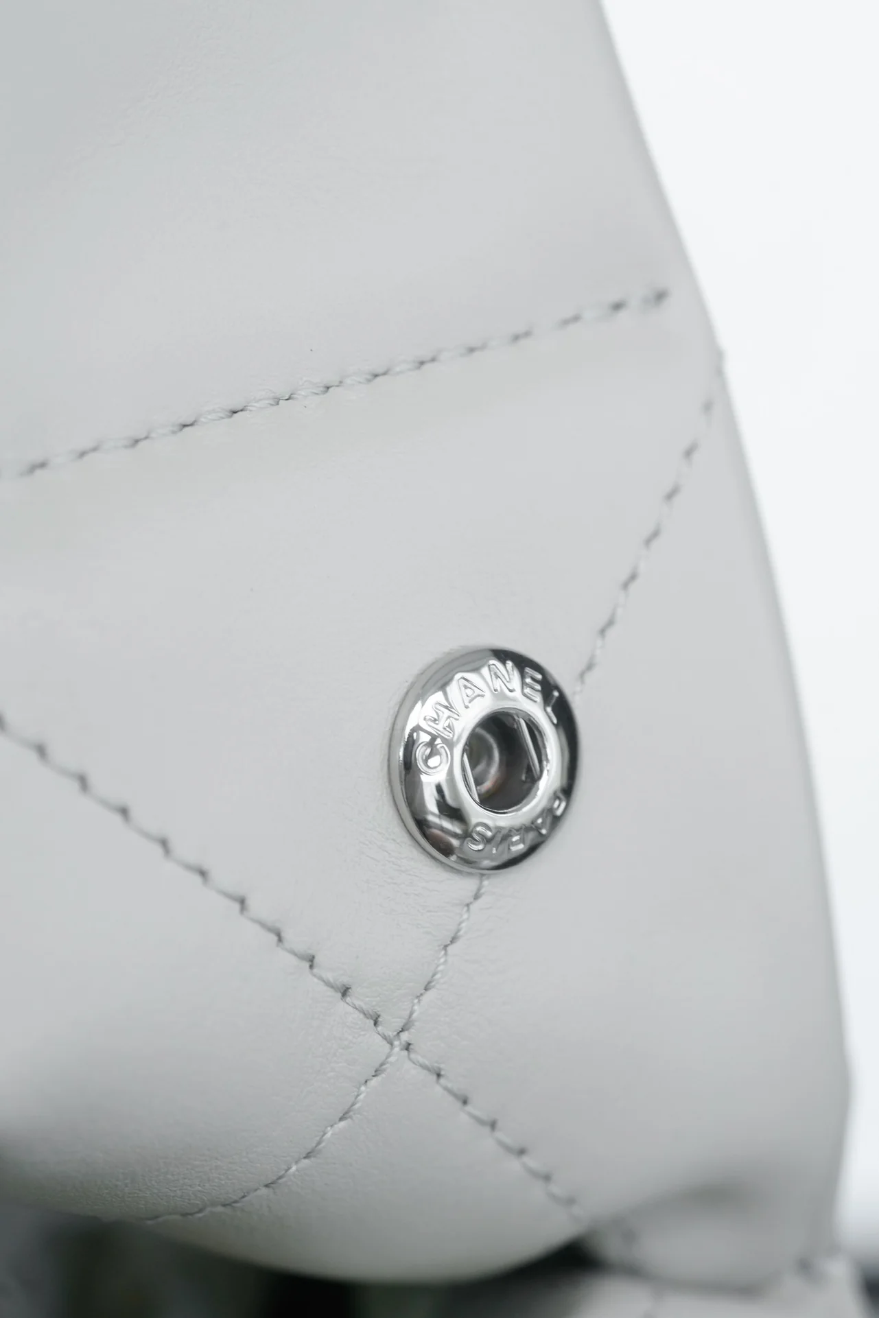 Маленькая белая сумочка Chanel с серебряной пряжкой на задней части.
