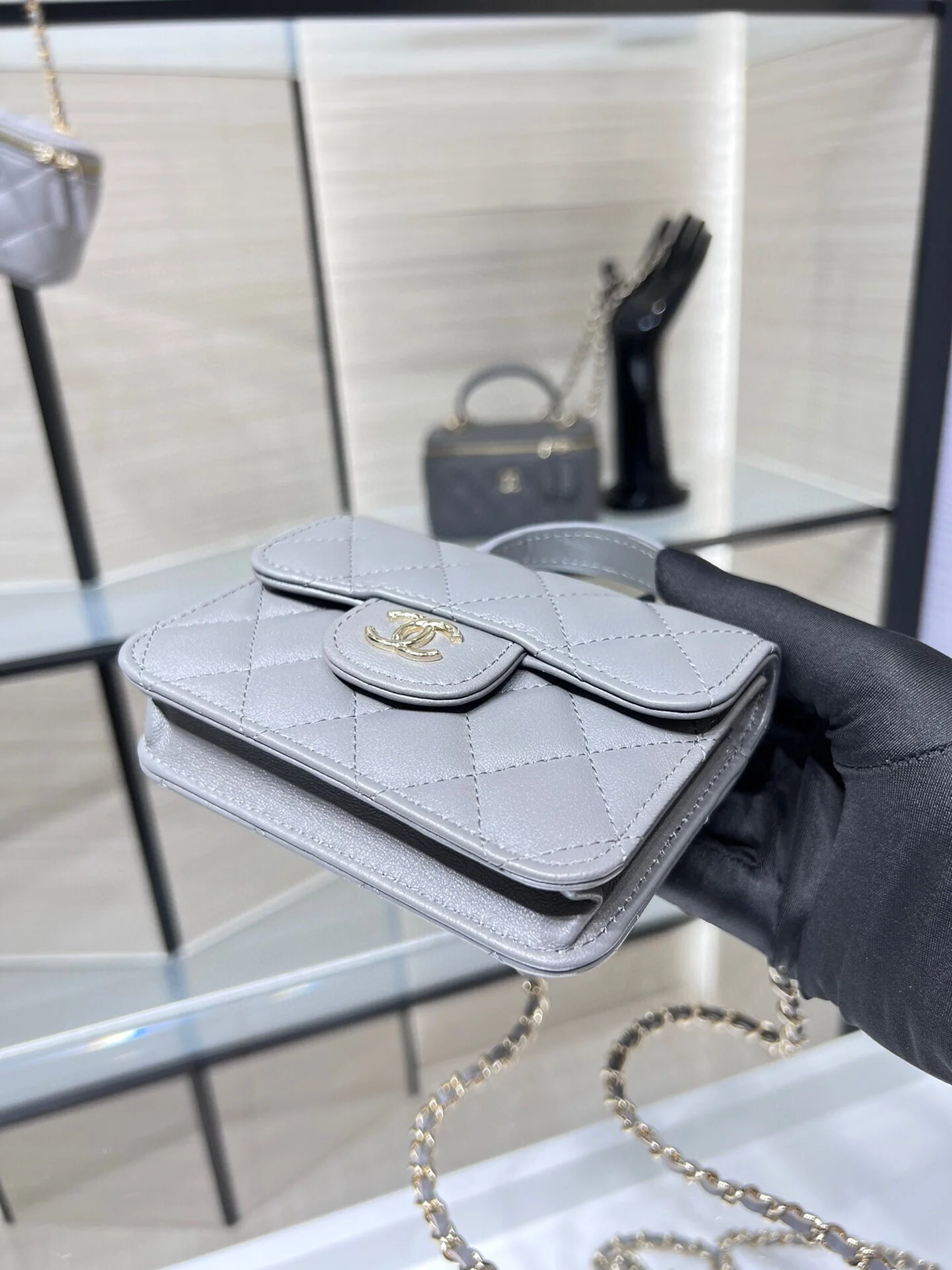 Сумка Chanel из коллекции Métiers d'Art 2022 года — маленькая сумка с цепочкой и ручкой — серая.