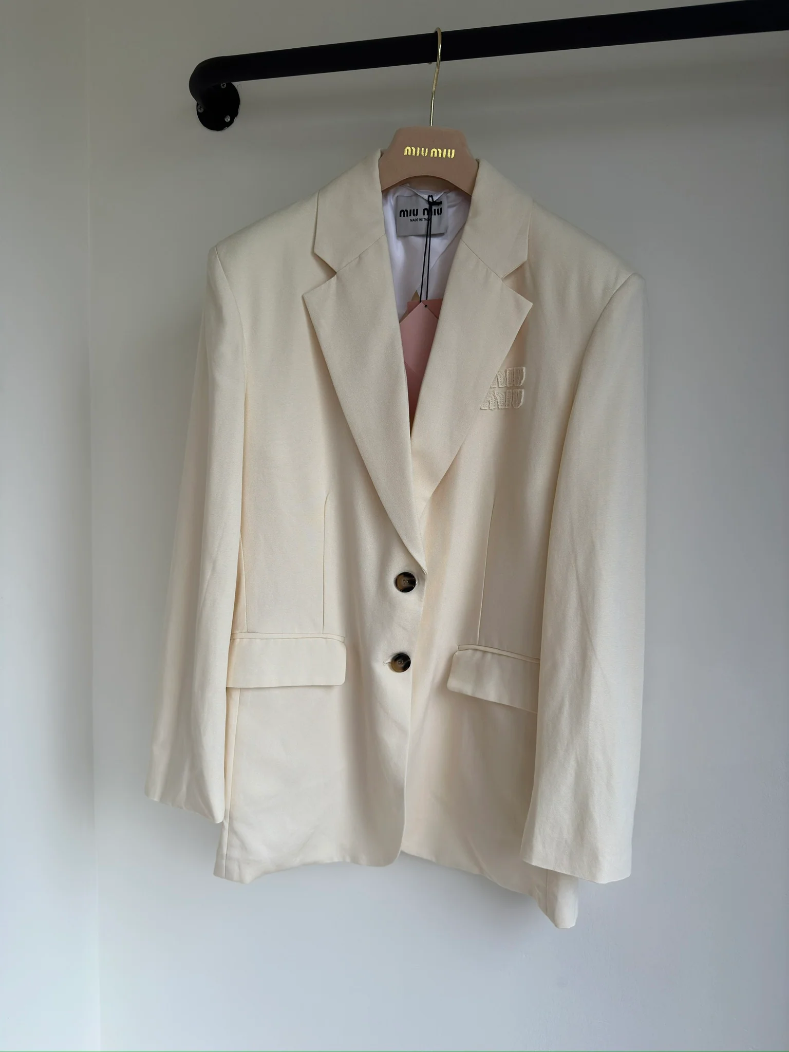 Новинка сезона весна/лето 2024 от Miu Miu - однобортный белый блейзер с буквенным логотипом.