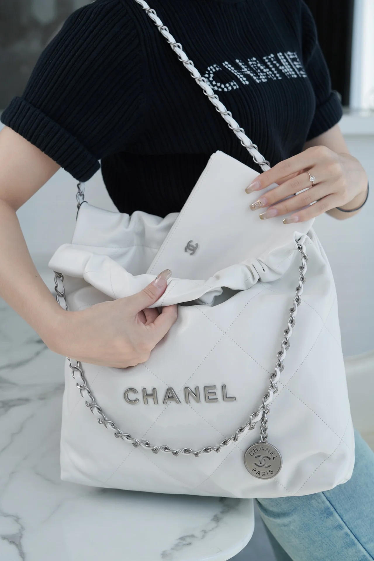 Сумочка Chanel No. 22 — маленькая, белая, серебристая.