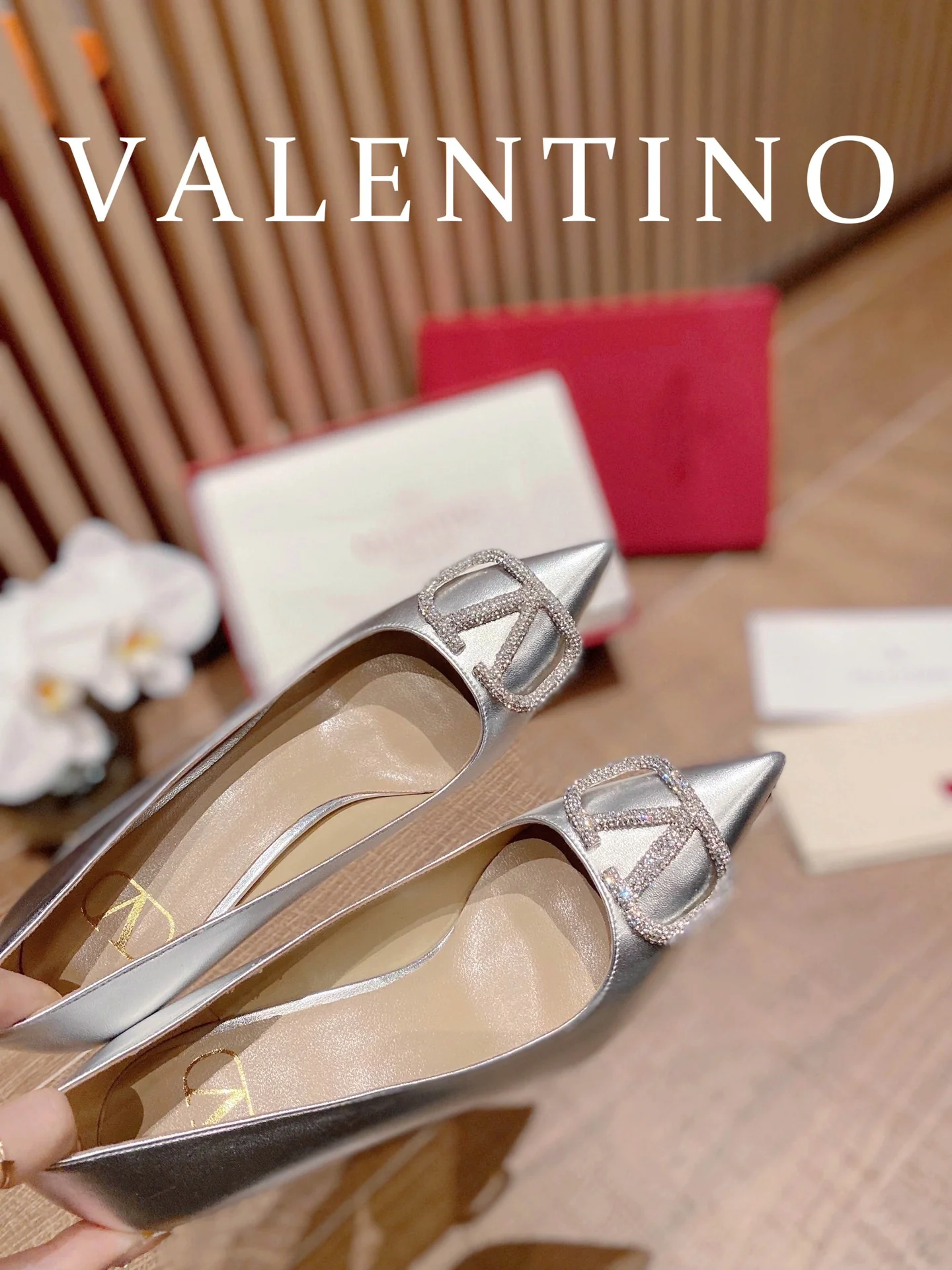 Туфли Valentino на каблуке с V-образным вырезом и бриллиантовой пряжкой — серебристые.