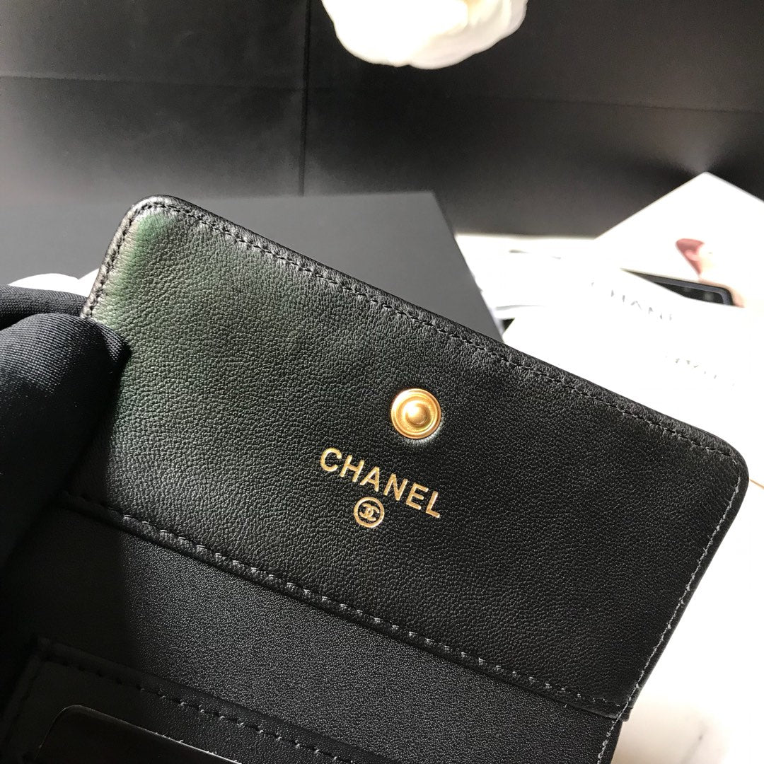 Кошелек Chanel Le Boy Tri-fold Wallet — из черной овечьей кожи с золотой пряжкой.