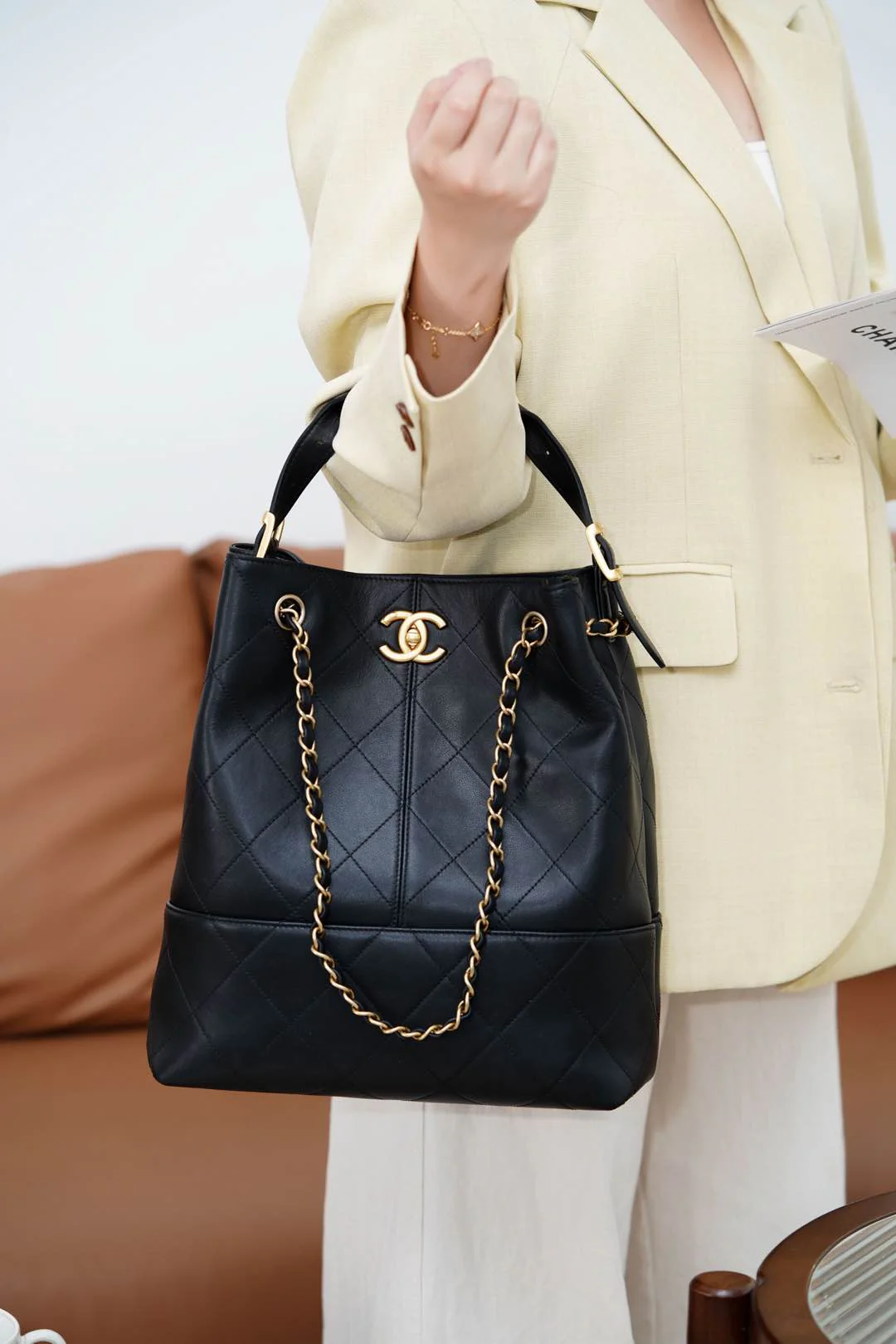 Сумка-ведро Chanel Métiers d'Art — черная с золотой фурнитурой.