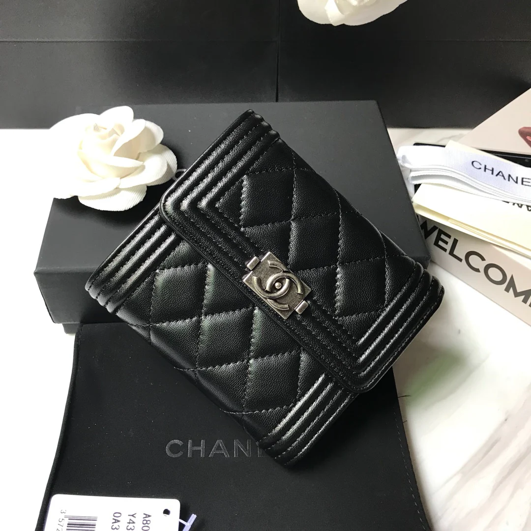 Кошелек Chanel Le Boy Tri-fold Wallet — из черной овечьей кожи с серебряной пряжкой.