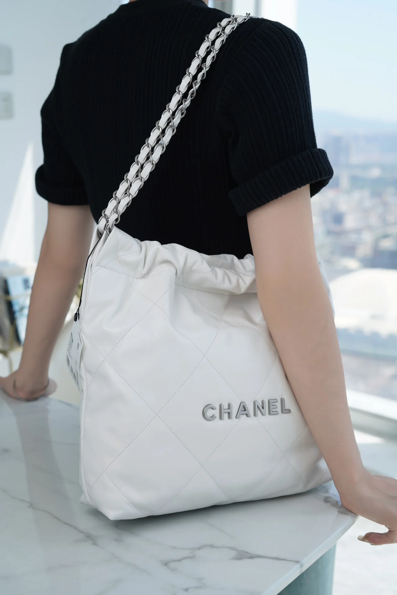 Сумочка Chanel No. 22 — маленькая, белая, серебристая.