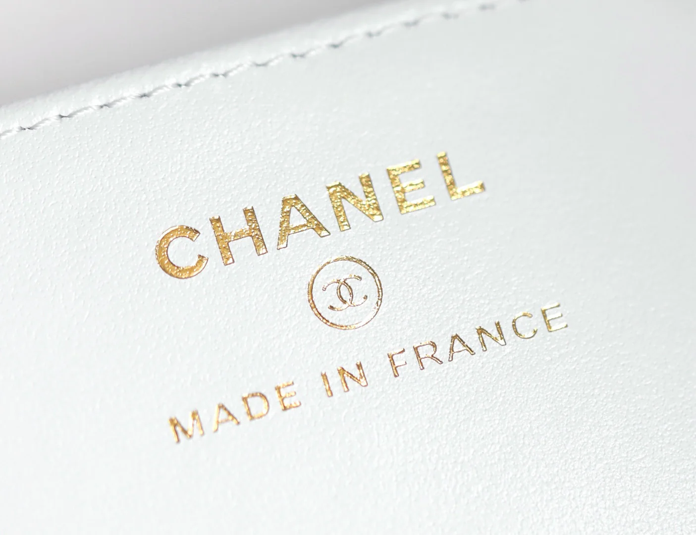 Мини-сумка-котелок Chanel 25p из овечьей кожи, белая с черной отделкой и светло-золотистой пряжкой.