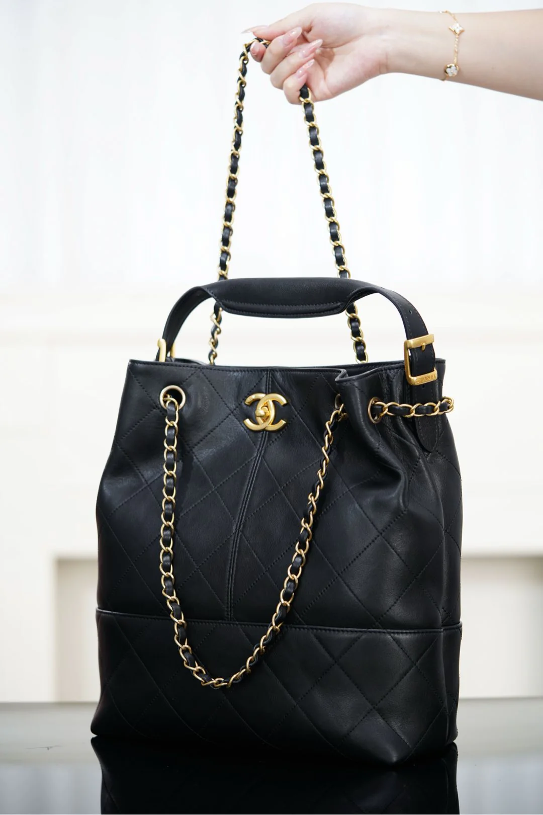 Сумка-ведро Chanel Métiers d'Art — черная с золотой фурнитурой.